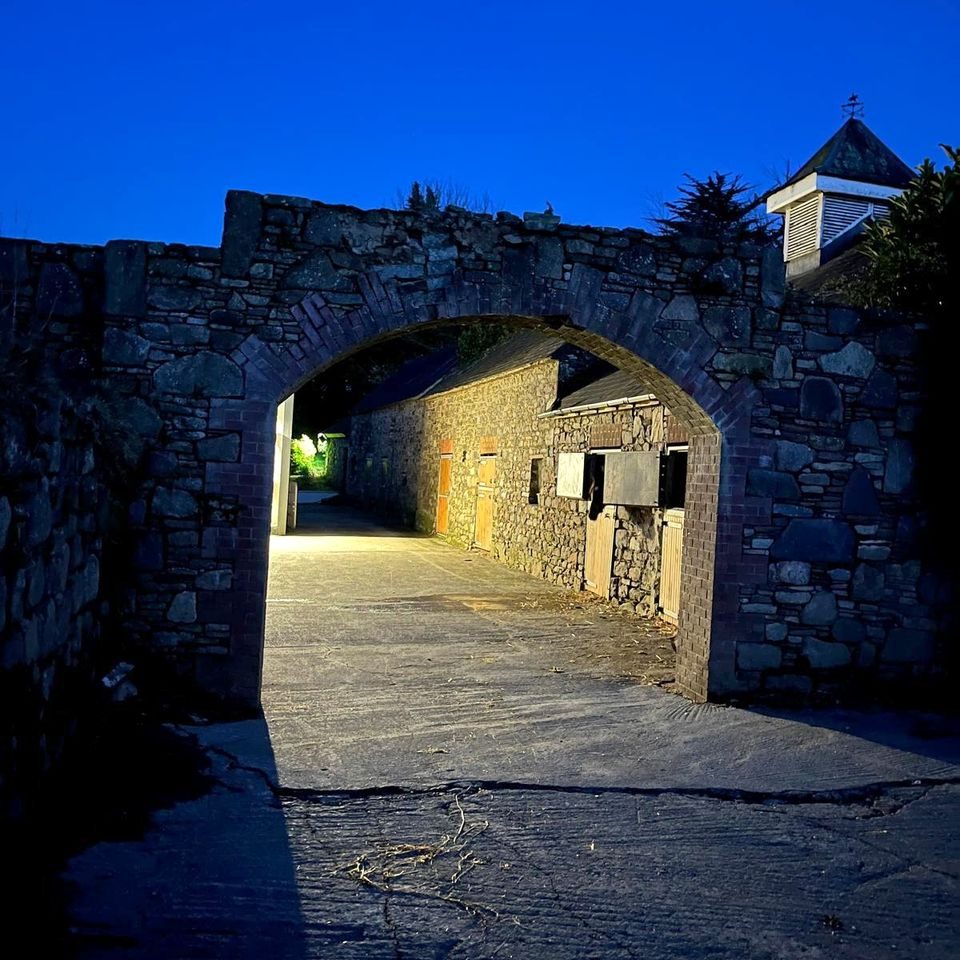 The stone archway into the stable yard, lit up at dusk